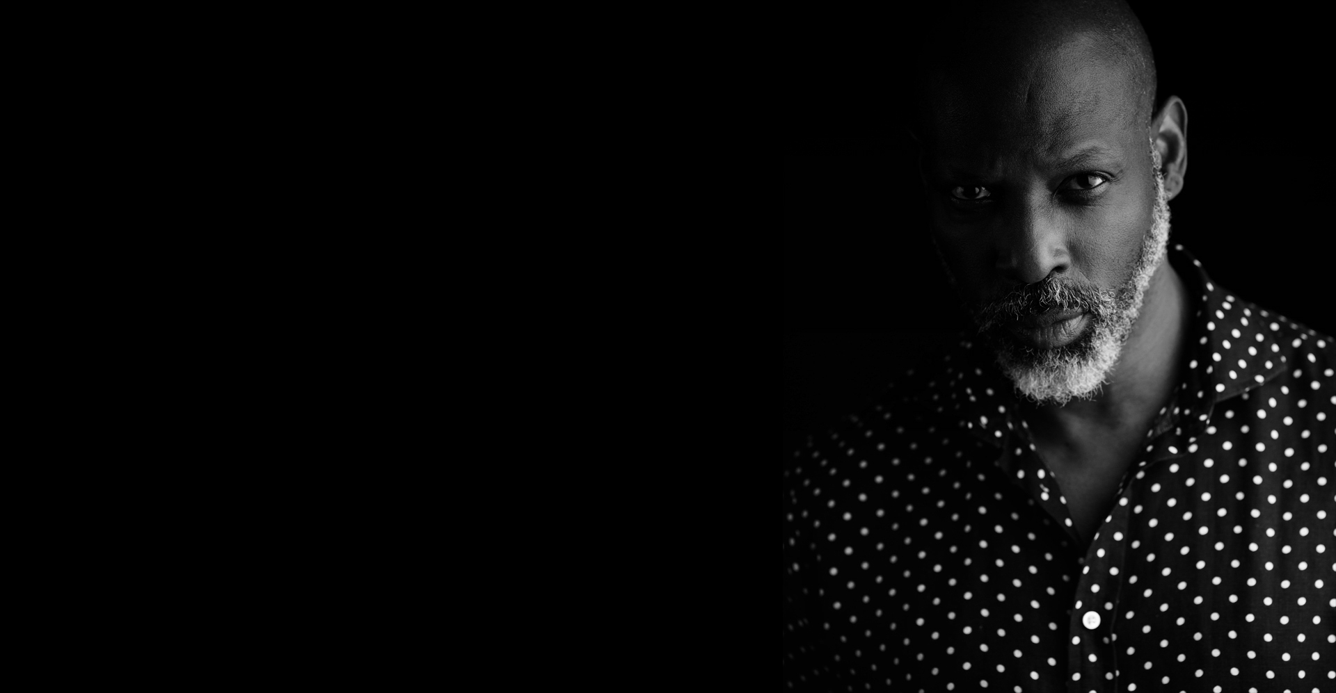 Black and white portrait of Aubrey K. Gardner in a polka dot shirt, dramatic low light